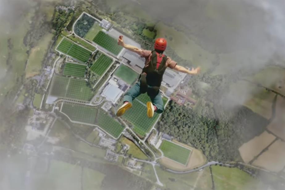 A man skydiving over a football field in England.