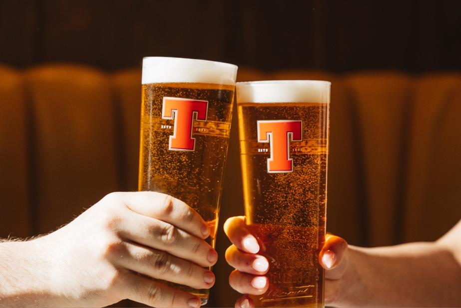 Two people clinking pints of Tennents Lager
