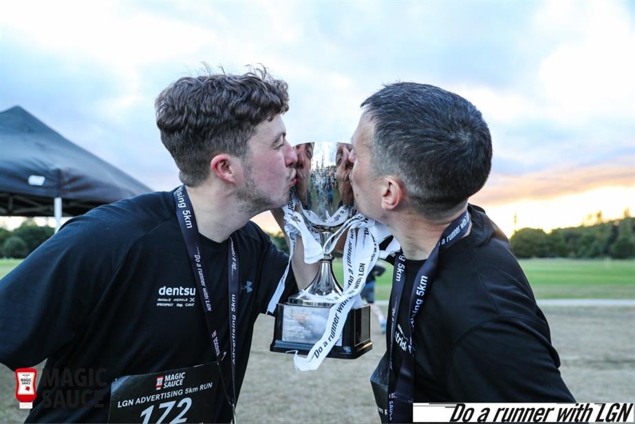 Dentsu runners kissing trophy