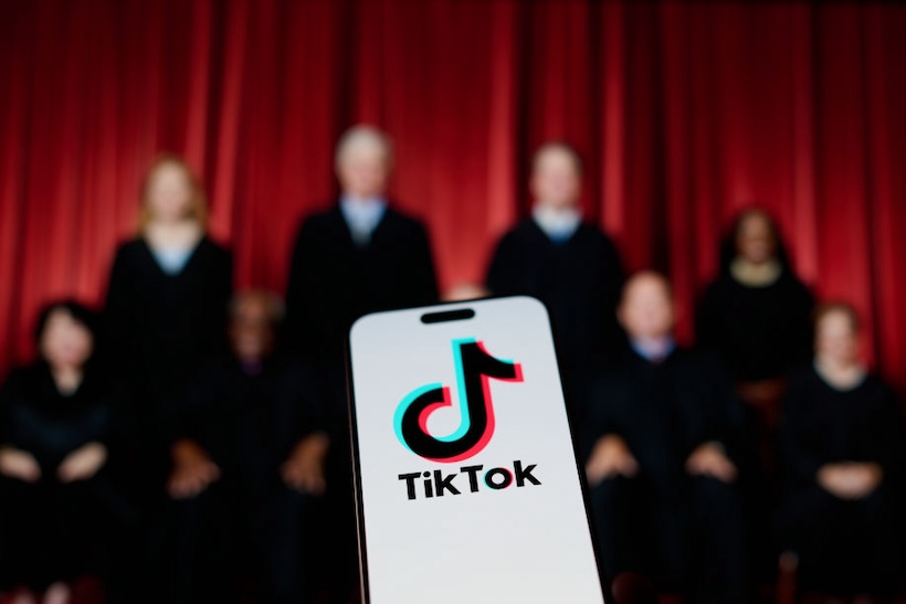 The TikTok app and logo are seen on a mobile device in this illustration photo, with the U.S. Supreme Court justices blurred out in the background